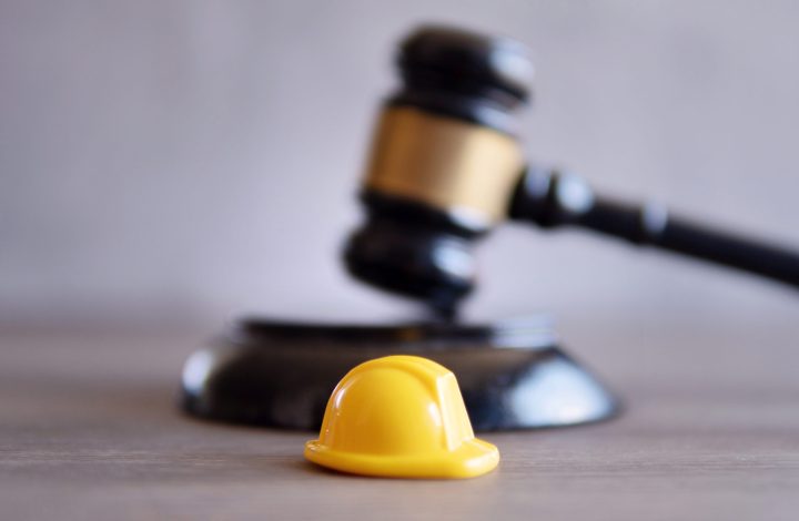 Closeup image of yellow hard hat and judge gavel. Labour law concept.